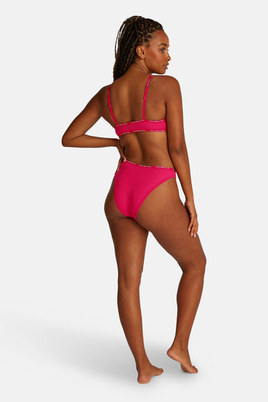 Roze slip van Tommy Jeans, met elastische band met logo rondom, gezien van achteren.
