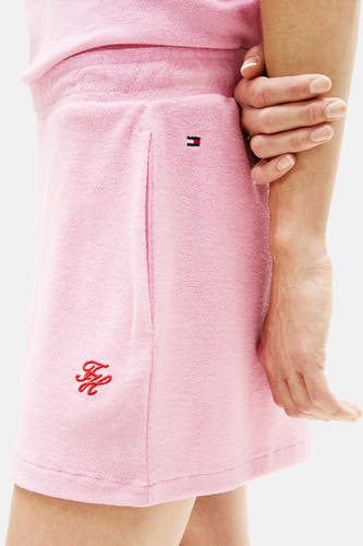 Roze badstof short van TOMMY JEANS, zijaanzicht met klein vlaglogo en rood geborduurd embleem.