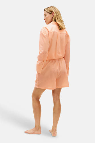 Short rayé orange de TOMMY JEANS avec texture seersucker, porté avec une blouse assortie, vu de dos.