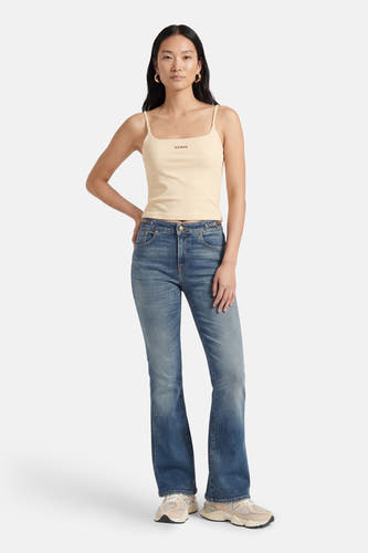 Beige top met spaghettibandjes van Guess, gedragen met blauwe jeans en crèmekleurige sneakers.