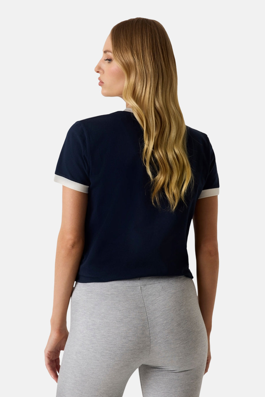Donkerblauwe korte mouwen t-shirt van Guess® met witte mouwbanden, rugzijde weergegeven op model in grijze broek