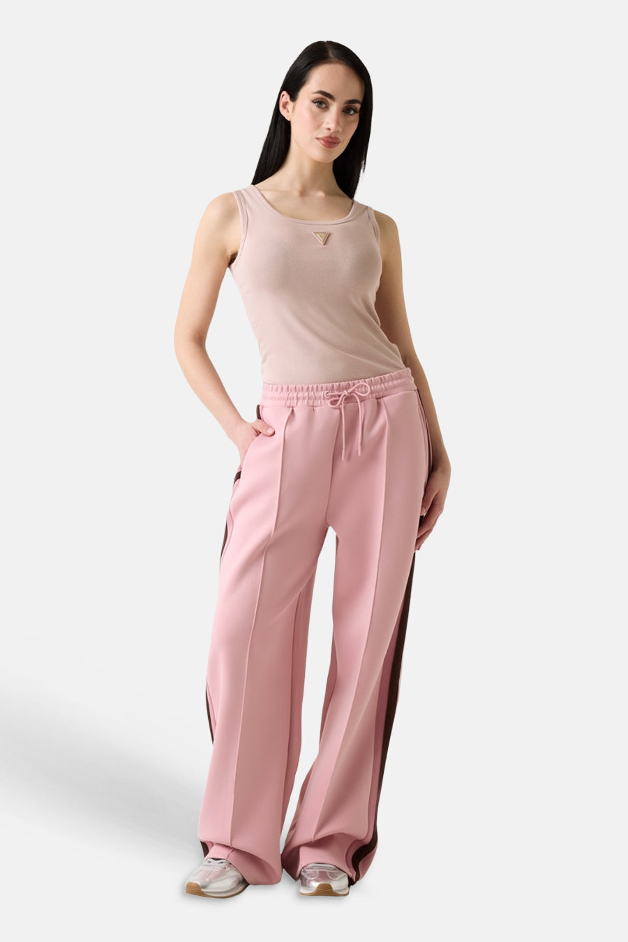 Roze tanktop van Guess® met klein driehoekig logo, gedragen met roze joggingbroek en witte sneakers, front view.