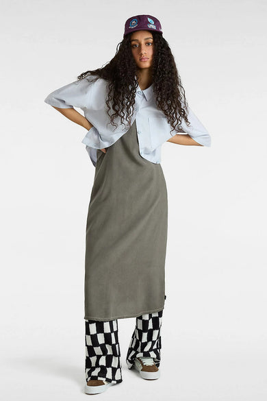 Blauw hemd met korte mouwen van VANS “OFF THE WALL”, gedragen over een grijze jurk met een geblokte broek.
