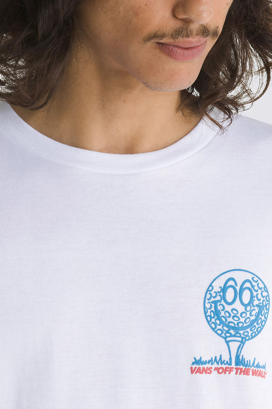 Een witte T-shirt met een blauwe golfbal print met een smiley face en de tekst "VANS 'OFF THE WALL'".

