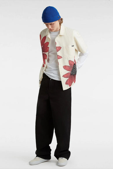 Chemise écru à manches courtes de VANS "OFF THE WALL" avec des motifs de fleurs rouges, associée à une chemise blanche à manches longues, un pantalon noir et des baskets blanches.