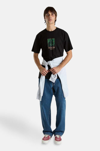 Zwart T-shirt met korte mouwen van VANS “OFF THE WALL”, met grafische print, gecombineerd met wijde jeans en een vest gestrikt om de middel.
