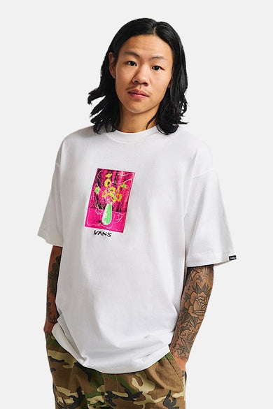 T-shirt blanc à manches courtes de Vans, avec imprimé floral sur la poitrine et pantalon camouflage.