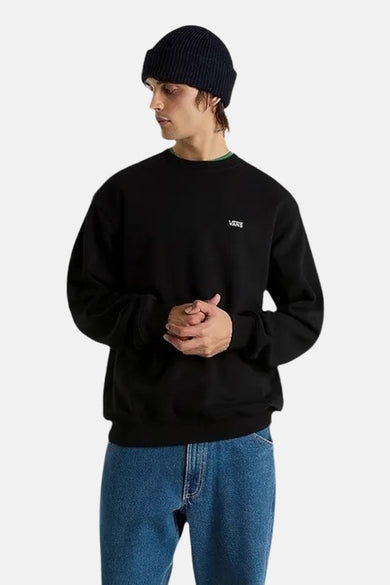 Pull-over noir de VANS "OFF THE WALL", avec des manches longues et un col rond, porté avec un bonnet et des jeans.