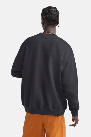 Zwarte sweater van VANS “OFF THE WALL”, gezien van achteren, met oranje shorts en zilveren ketting.

