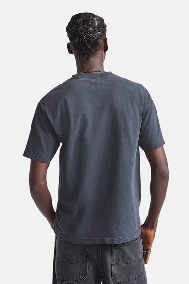 Zwart T-shirt met korte mouwen van VANS “OFF THE WALL”, gezien van achteren, gecombineerd met een grijze broek.
