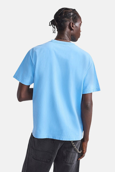 Blauw T-shirt met korte mouwen van VANS “OFF THE WALL”, gezien van achteren, gecombineerd met een zwarte broek met ketting.
