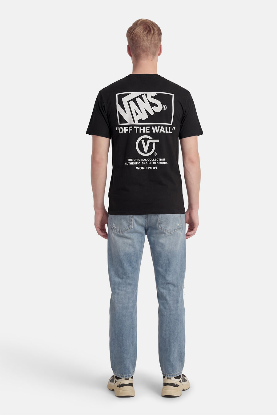 Zwart T-shirt van VANS “OFF THE WALL” met witte merklogo en tekstprint op de rug, gedragen met een blauwe jeans en sneakers.
