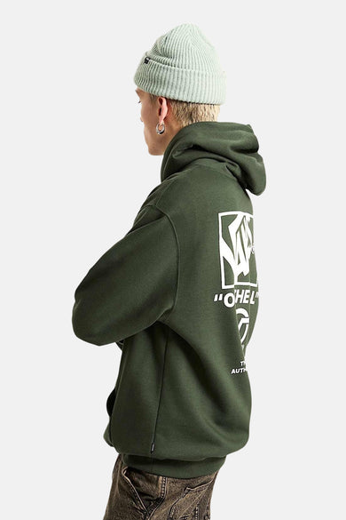 Groene sweater met kap van VANS “OFF THE WALL”, met witte print op de rug, gedragen met een groene muts.
