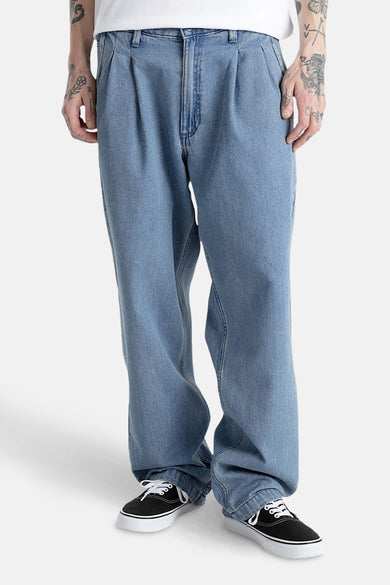 Jean décontracté en denim bleu moyen de VANS "OFF THE WALL", avec des plis et des chaussures noires.