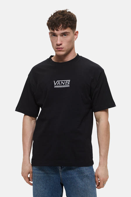 Zwart T-shirt met korte mouwen van VANS, met een wit logo en een dambordpatroon op de borst, gedragen met een blauwe jeans.
