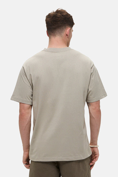 Beige T-shirt met korte mouwen van VANS “OFF THE WALL”, gezien van achteren, gedragen met een kralenarmband.
