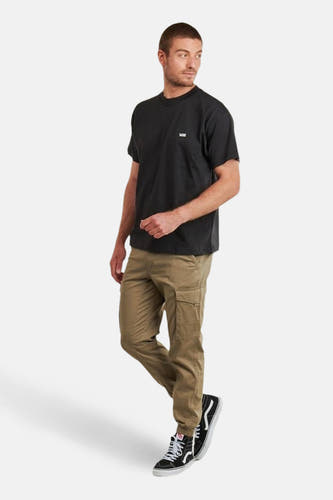 Zwart T-shirt met korte mouwen van VANS, gedragen met kaki broek en zwart-witte hoge sneakers.