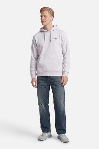 Grijze sweater met kap van VANS “OFF THE WALL”, met een klein logo op de borst, gecombineerd met blauwe jeans met scheuren en grijze sneakers.
