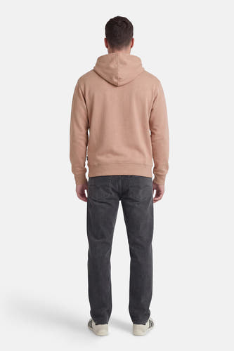 Beige sweater met kap van VANS “OFF THE WALL”, gezien van de achterkant, gedragen met donkergrijze jeans en sneakers.