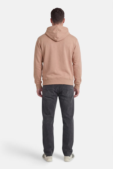 Beige sweater met kap van VANS “OFF THE WALL”, gezien van de achterkant, gedragen met donkergrijze jeans en sneakers.