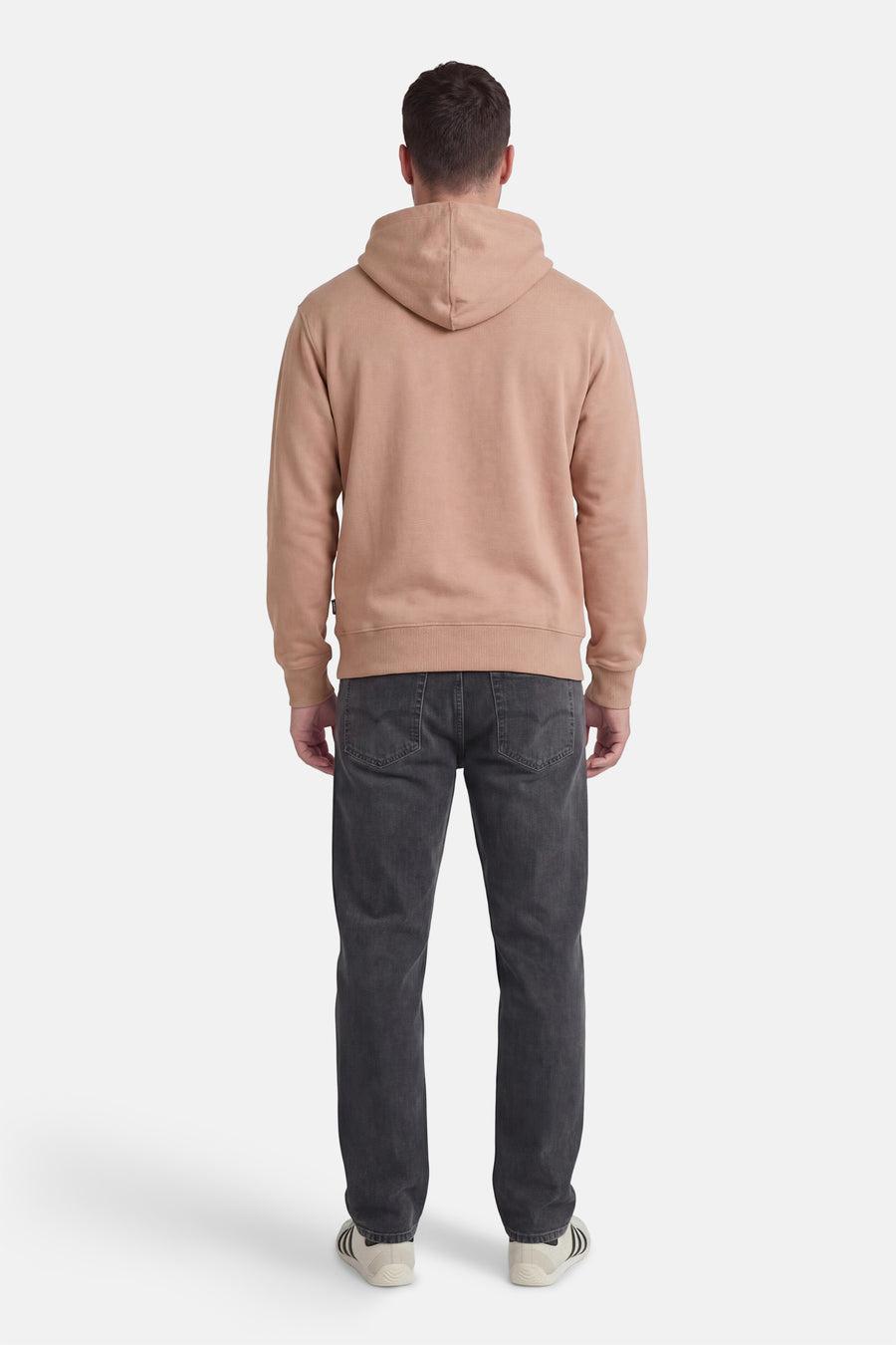 Beige sweater met kap van VANS “OFF THE WALL”, gezien van de achterkant, gedragen met donkergrijze jeans en sneakers.