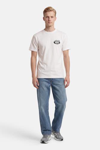 Wit T-shirt van VANS “OFF THE WALL” met zwart logo op de borst, gedragen door een man met blauwe jeans en grijze sneakers.