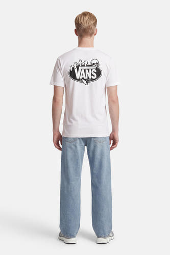 Wit T-shirt van VANS met schedel- en handopdruk op de rug, gedragen met een lichtblauwe jeans en grijze sneakers.