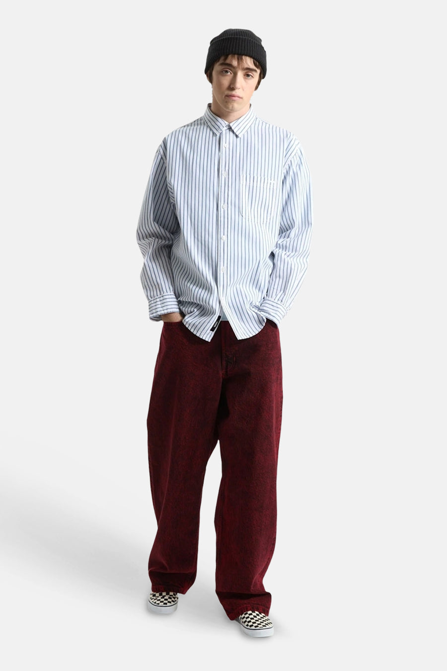 Blauw-wit gestreept overhemd met lange mouwen van VANS “OFF THE WALL”, oversized pasvorm, gedragen met zwarte muts, rode broek en geruite slip-ons.