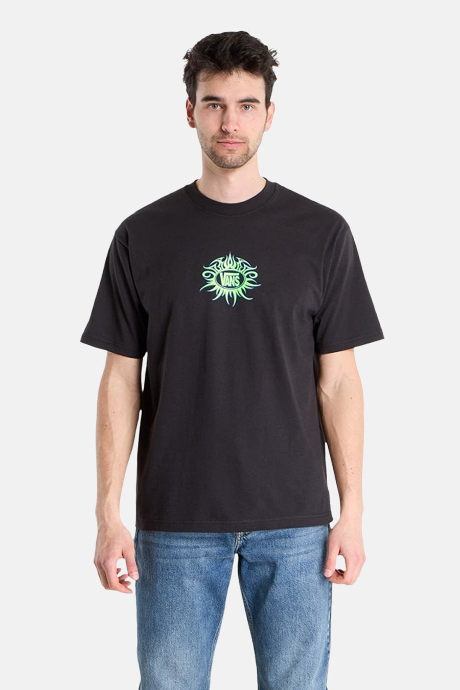Zwart T-shirt van VANS “OFF THE WALL” met korte mouwen en groen logo op de borst, gedragen met een jeansbroek.
