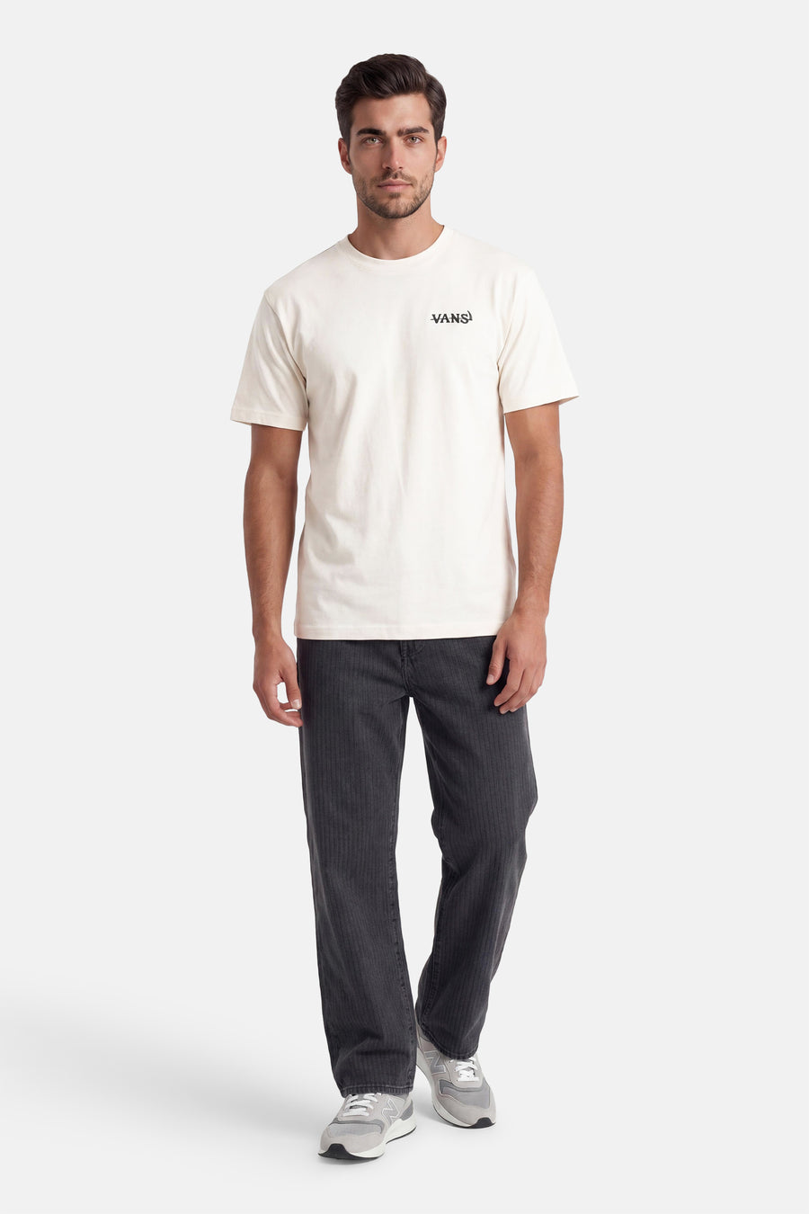 Ecru T-shirt met korte mouwen van VANS “OFF THE WALL” met zwart logo op de borst, gedragen bij een donkergrijze ribbroek en grijze sneakers.
