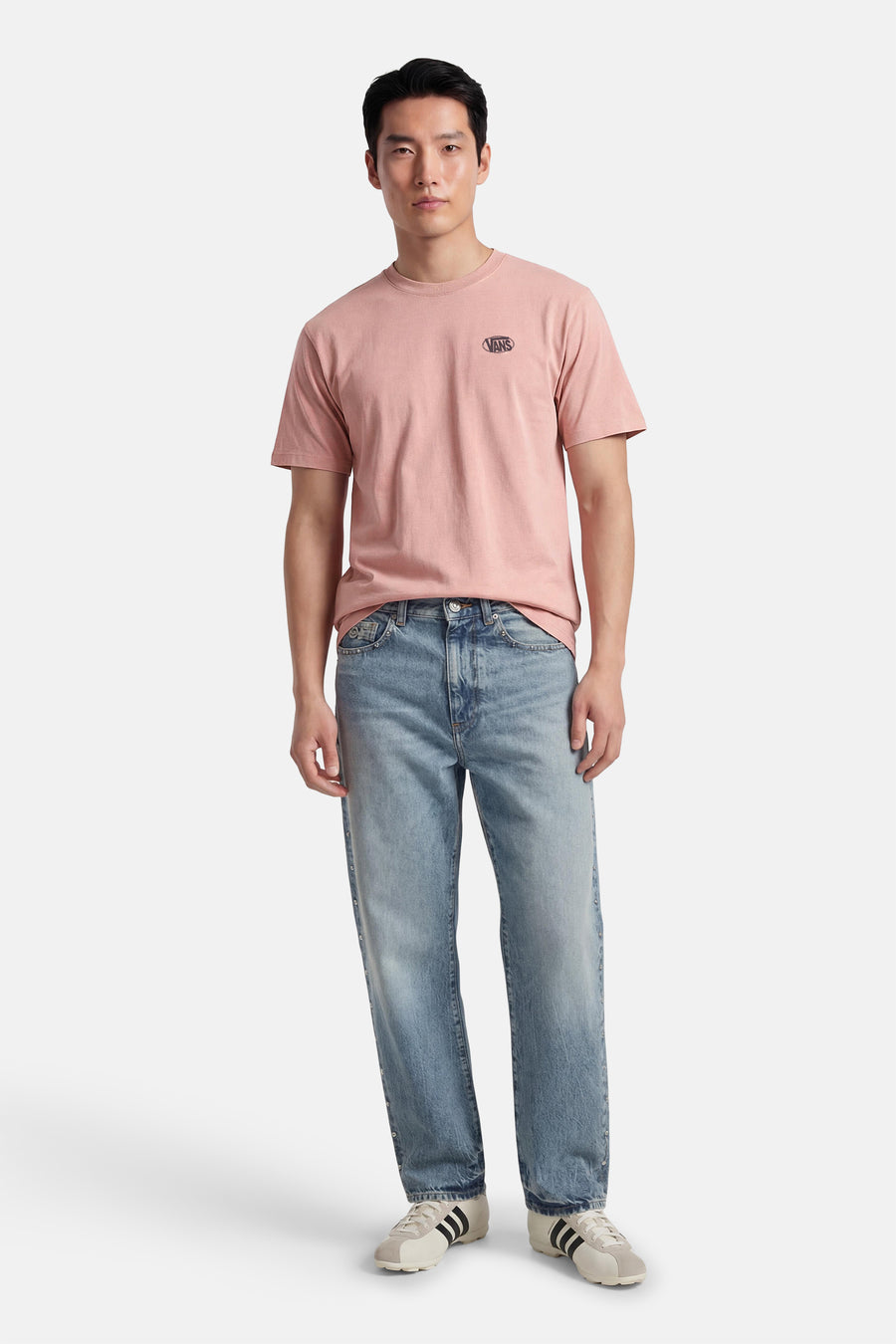 Roze T-shirt van VANS “OFF THE WALL”, met korte mouwen, gedragen met jeans en crèmekleurige schoenen.
