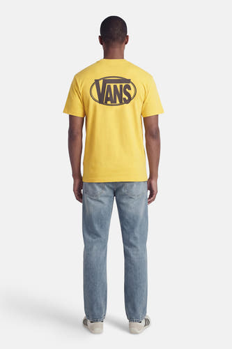 Geel T-shirt met korte mouwen van VANS "OFF THE WALL", met een ovale graphic op de rug, gedragen met jeans en sportschoenen.
