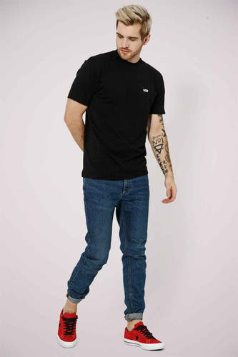 Zwart T-shirt van Vans, gedragen met jeans en rode sneakers.