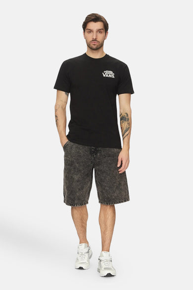 Man in zwarte Vans T-shirt en gewassen denim shorts.