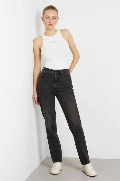 Grijze mom jeans van Guess, met een hoge taille en rechte pijpen, gecombineerd met een wit hemdje en crèmekleurige sneakers.
