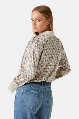 Chemise beige à longues manches de Guess, avec un motif logo répétitif, portée avec des jeans bleus et une ceinture.