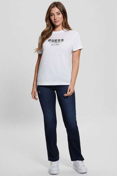 Wit T-shirt met korte mouwen van Guess met zwarte 'Guess Los Angeles Est. 1981' opdruk, gecombineerd met donkerblauwe jeans en witte sneakers.