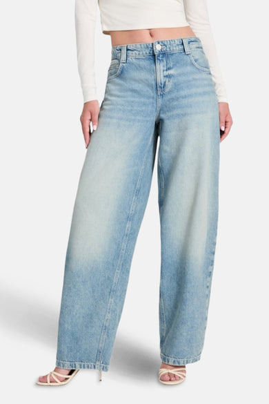 Lichtblauwe denim jeans met wijde pijpen van Guess, gecombineerd met een wit shirt en sandalen.