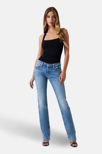 Jeans straight van lichtblauwe denim van Guess, gedragen met een zwarte top en sandalen met bandjes.