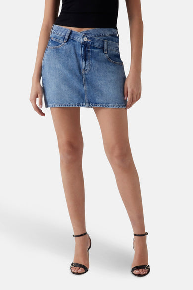 Korte blauwe rok van Guess, gestyled met een zwarte top en zwarte open schoenen met hak.
