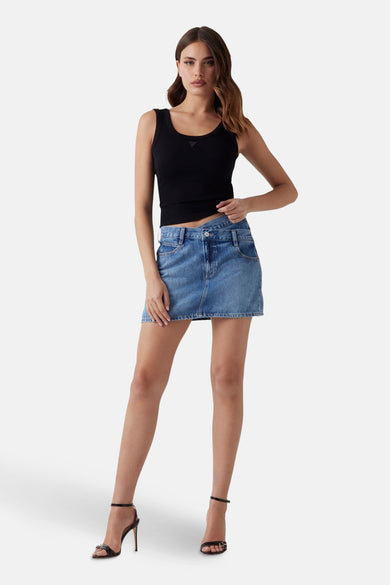 Blauwe korte rok van Guess, met denim textuur, gecombineerd met een zwarte top en hakken.
