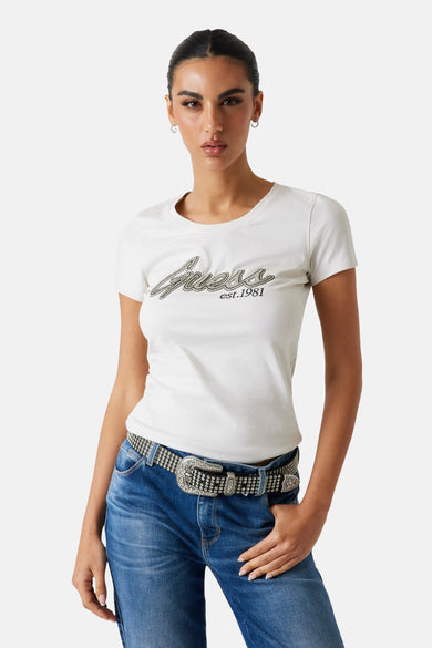 Wit T-shirt met korte mouwen van Guess, met glitters en de tekst "est. 1981", gedragen met een jeans en riem.
