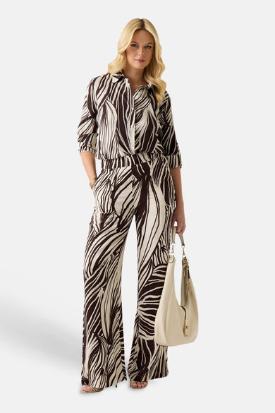 Pantalon de couleur crème avec motif abstrait marron foncé de Guess, à jambes larges et passants de ceinture.