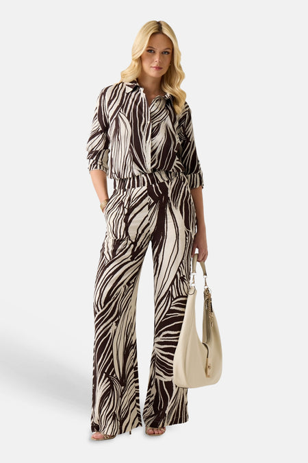 Pantalon de couleur crème avec motif abstrait marron foncé de Guess, à jambes larges et passants de ceinture.
