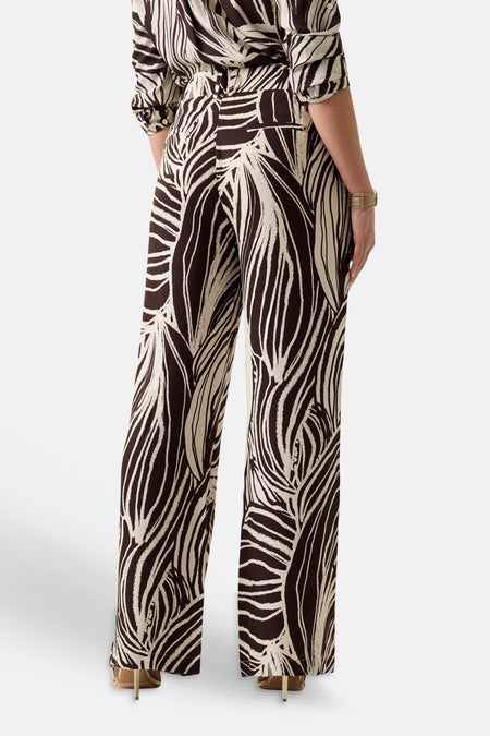 Multicolor broek van Guess® met abstract bruin-beige bladmotief, wijde pijpen, gedragen door een model met bijpassende top, in rugzicht.