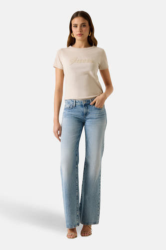 T-shirt beige à manches courtes de Guess, porté avec un jean ample et des sandales dorées.