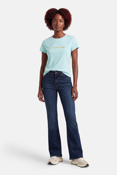 Blauw T-shirt met korte mouwen van Guess®, met de tekst "Dump Him" in gouden strassteentjes, gecombineerd met donkere jeans en sneakers.
