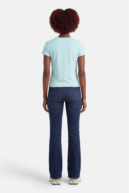 Blauw T-shirt met korte mouwen van Guess®, gezien van achteren, gecombineerd met donkerblauwe spijkerbroek en witte sneakers.