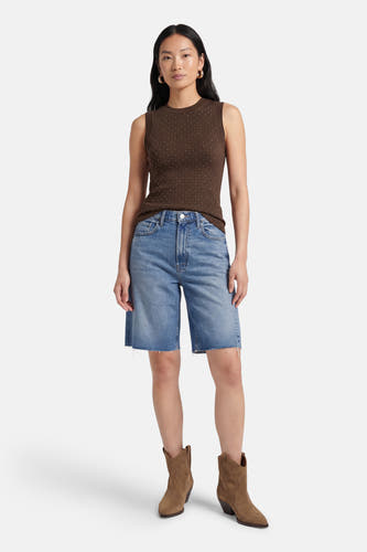 Bruine mouwloze top van Guess met kleine witte stippen, gedragen met lichtblauwe denim shorts en bruine suède cowboylaarzen.