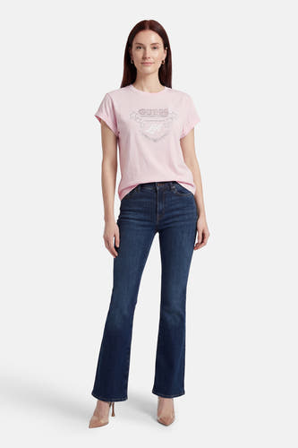 Roze T-shirt met korte mouwen van Guess, met strass logo en sterren print, gedragen met donkere jeans en hoge hakken.
